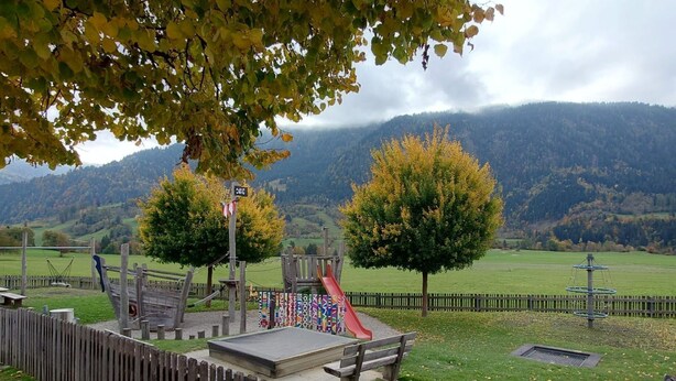 A playground with a slide, climbing structures, and a fenced area with benches. - Apartment Günter by Interhome (Sagogn)