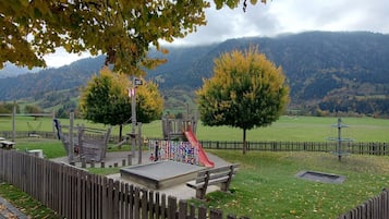Ein Spielplatz mit Rutsche, Klettergerüsten und einem eingezäunten Bereich mit Bänken.