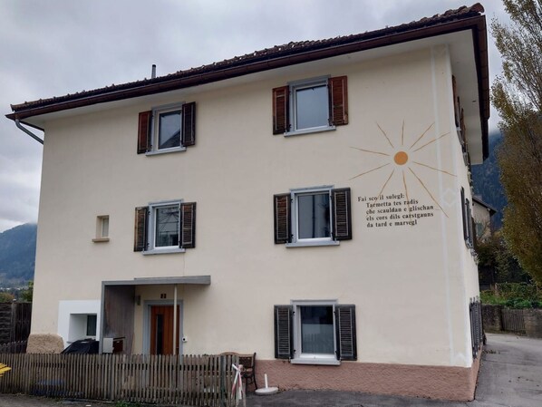 Un bâtiment à deux étages, doté de nombreuses fenêtres, d’un symbole solaire et d’un texte dans une langue étrangère.