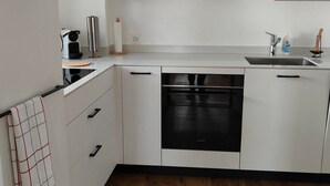 A modern kitchen with white cabinets, a built-in oven, and a wooden floor. - Apartment Günter by Interhome (Sagogn)