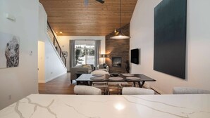 A modern dining area with a marble table, wooden ceiling, and a fireplace. - The Drift at Firelight | Big Sky Adventure+Hot Tub (Big Sky)