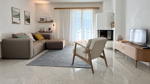 A modern living room with a sofa, a chair, a TV, and a fireplace. - Familienfreundliche und gemütliche 3.5 Wohnung mit Garten by Interhome (Laax)