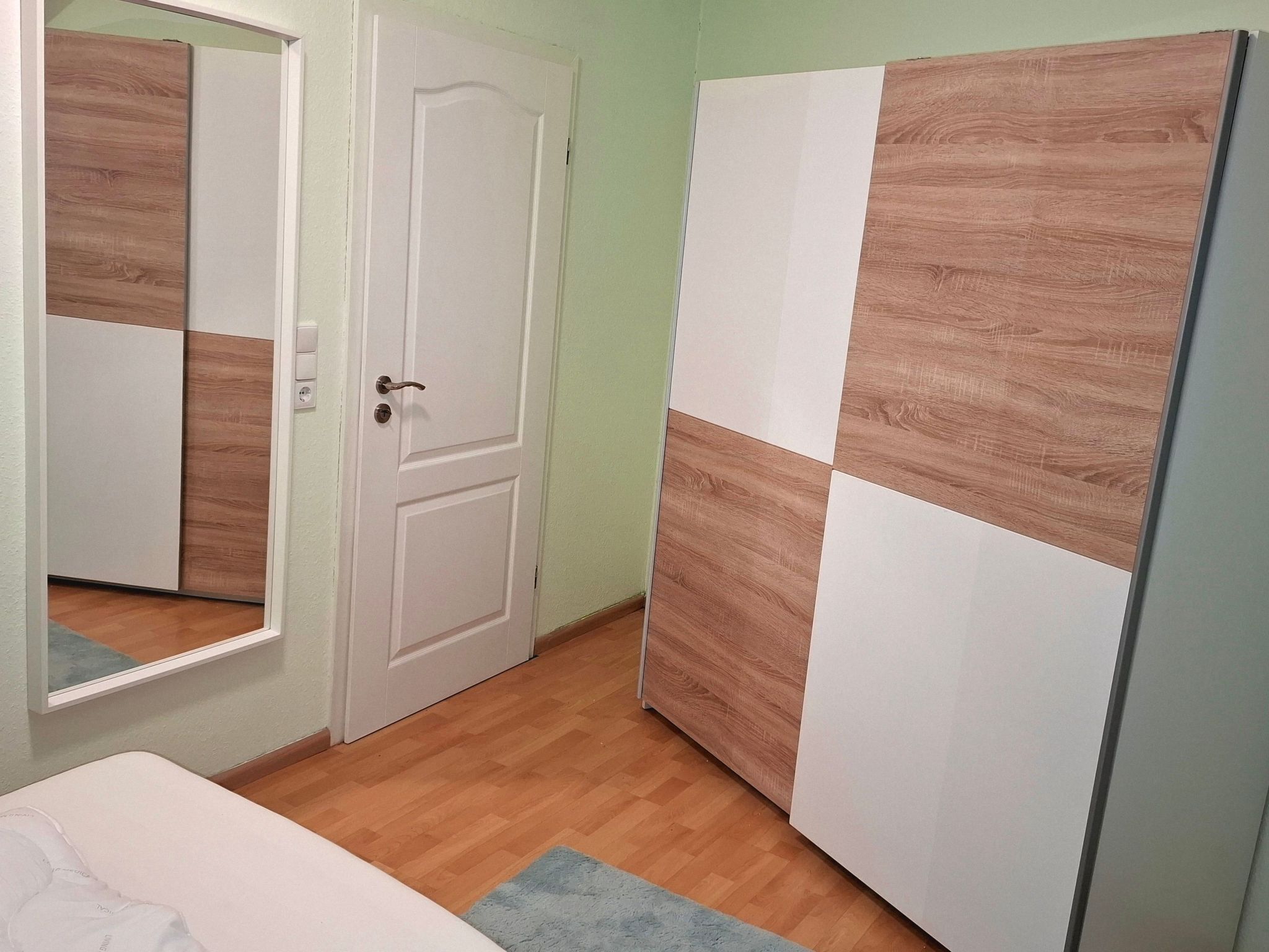 Ein Zimmer mit Holzboden, einer weißen Tür und einem Schrank mit Holzpaneelen.