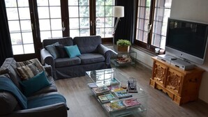 Ein Wohnzimmer mit einer Couch, einem Couchtisch mit Zeitschriften, einem Fernseher und einem Holzschrank.