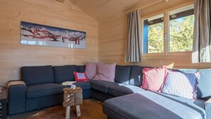 Una sala de estar acogedora con un sofá modular, un taburete de madera y un tapiz de cuero de vaca.