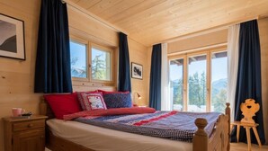 Un dormitorio de cabaña de madera con cama, mesita de noche y vistas al exterior.