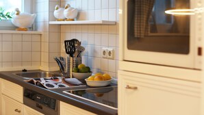 A modern kitchen with white cabinets, a stainless steel sink, and a built-in oven. - in Westerland mit Sonniger Terrasse by Interhome (Archsum)