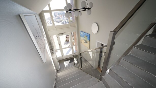 A modern staircase with glass railings, leading to an upper floor with large windows and a view of the street. - in Westerland mit Sonniger Terrasse by Interhome (Archsum)