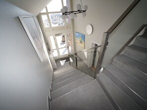 A modern staircase with glass railings, leading to an upper floor with large windows and a view of the street. - in Westerland mit Sonniger Terrasse by Interhome (Archsum)