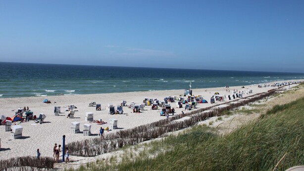 A beach with rows of beach chairs and umbrellas, a sandy shore, and the ocean in the background. - Strandfloh in Hörnum by Interhome (Hörnum)
