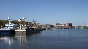 A harbor with various boats docked, a large industrial building, and a clear sky. - Strandfloh in Hörnum by Interhome (Hörnum)