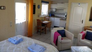 A compact room with a bed, a small desk, a chair, and a kitchenette. - Strandfloh in Hörnum by Interhome (Hörnum)