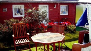 A red brick house with a small garden, a wooden table and chairs, and a blue awning. - Strandfloh in Hörnum by Interhome (Hörnum)