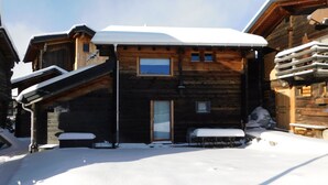 Eine Holzhütte mit verschneitem Dach und einer kleinen Veranda.
