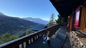 Una terraza de madera con una mesa, una botella de vino y copas.