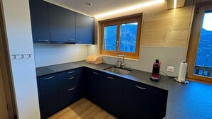 Una cocina moderna con armarios oscuros, encimera de madera, ventana con vistas y un lavabo integrado.