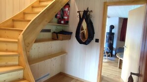 A wooden staircase leading to a loft area with a fire extinguisher and a coat rack. - Chalet Männertreu OG by Interhome (Bellwald)