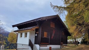 A wooden cabin with a white front section, a staircase leading to the entrance, and a ski rack on the side. - Chalet Männertreu OG by Interhome (Bellwald)