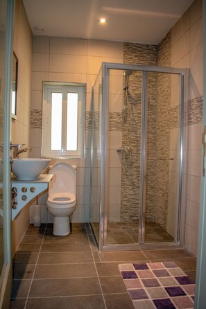 Ein Badezimmer mit Duschkabine, Waschbecken, Toilette und Spiegel.
