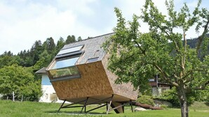 Uma casa moderna com telhado inclinado, janelas amplas e fachada de madeira.