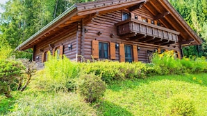 A log cabin with a balcony, surrounded by lush greenery and tall trees. - Glocknerhaus by Interhome (Berg im Drautal)