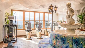 An indoor gym with exercise equipment, a large window with a mountain view, and a statue. - Glocknerhaus by Interhome (Berg im Drautal)
