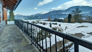 A stone-paved balcony with a metal railing overlooking a snowy landscape with mountains in the distance. - Glocknerhaus by Interhome (Berg im Drautal)