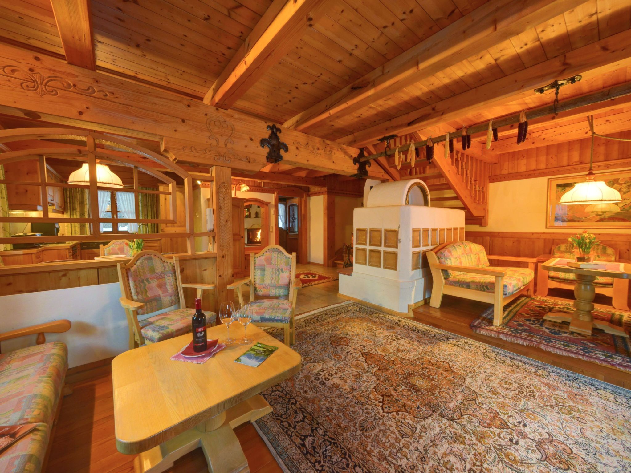 A cozy wooden cabin interior with a dining area, two sofas, a small table, and a fireplace.