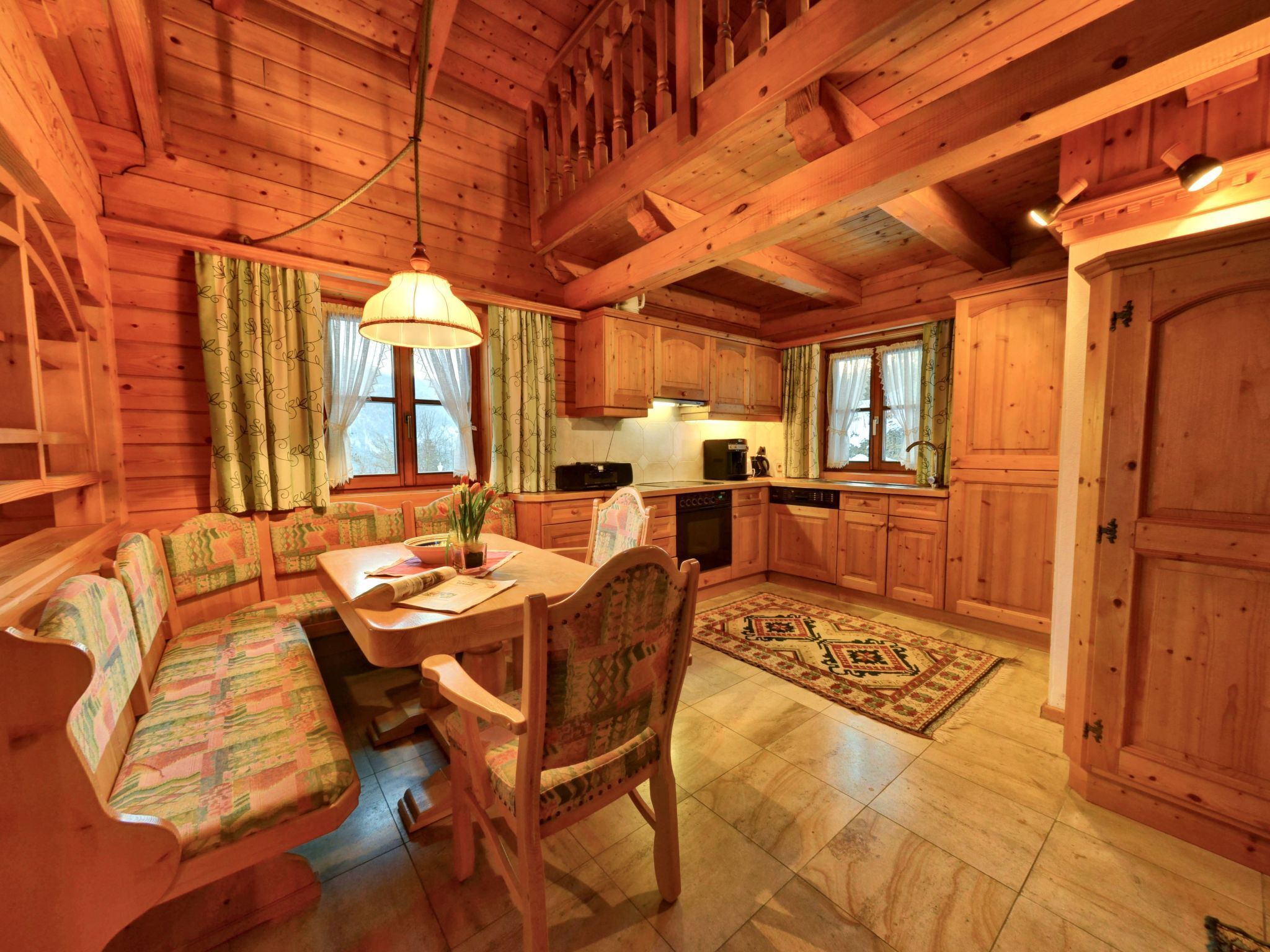 A cozy cabin-style kitchen with wooden walls and a dining area featuring a table and benches.
