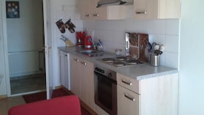 A compact kitchen with a stove, oven, and a coffee maker. There are cabinets and a sink.
