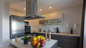Una cocina moderna con una isla central, electrodomésticos de acero inoxidable y un frutero.