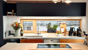 Una cocina moderna con un amplio ventanal, armarios de madera, una cafetera y un frutero.