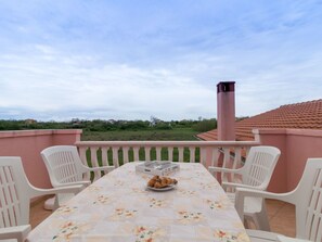 Eine Terrasse mit Tisch für zwei Personen, Stühlen und einem Teller mit Croissants.