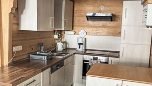 Eine kleine Küche mit Holzausstattung, einem Einbauofen und einer Kaffeemaschine.