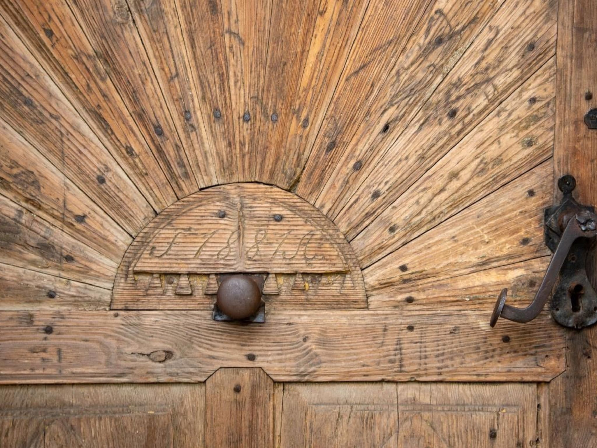 Une porte en bois avec une poignée en métal et un élément décoratif en métal.