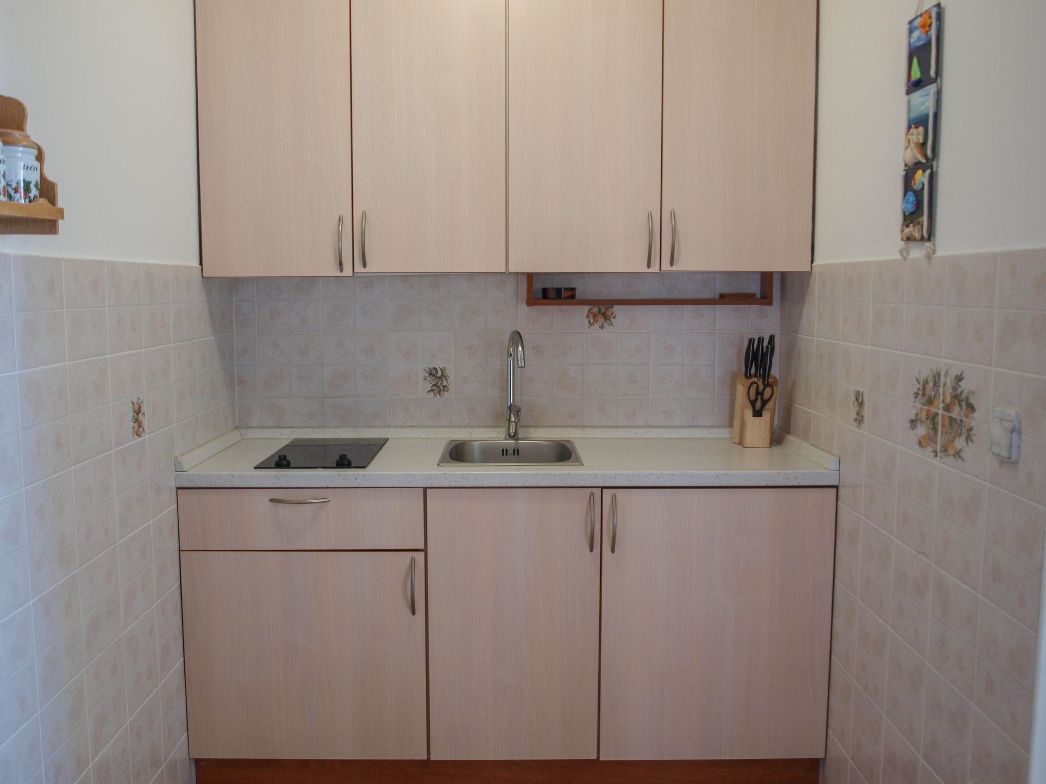 A kitchen with light-colored cabinets, a sink, and a countertop.