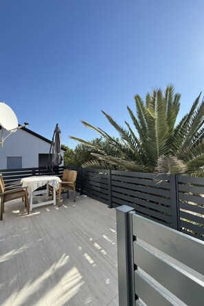 A patio area with a table and chairs, a satellite dish, and a palm tree. - Wohnung Vir 02 in Strandnähe - Agentur TA Leut by Interhome (Vir)