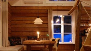 L’intérieur d’un chalet chaleureux, avec une table à manger en bois, un banc et un escalier.