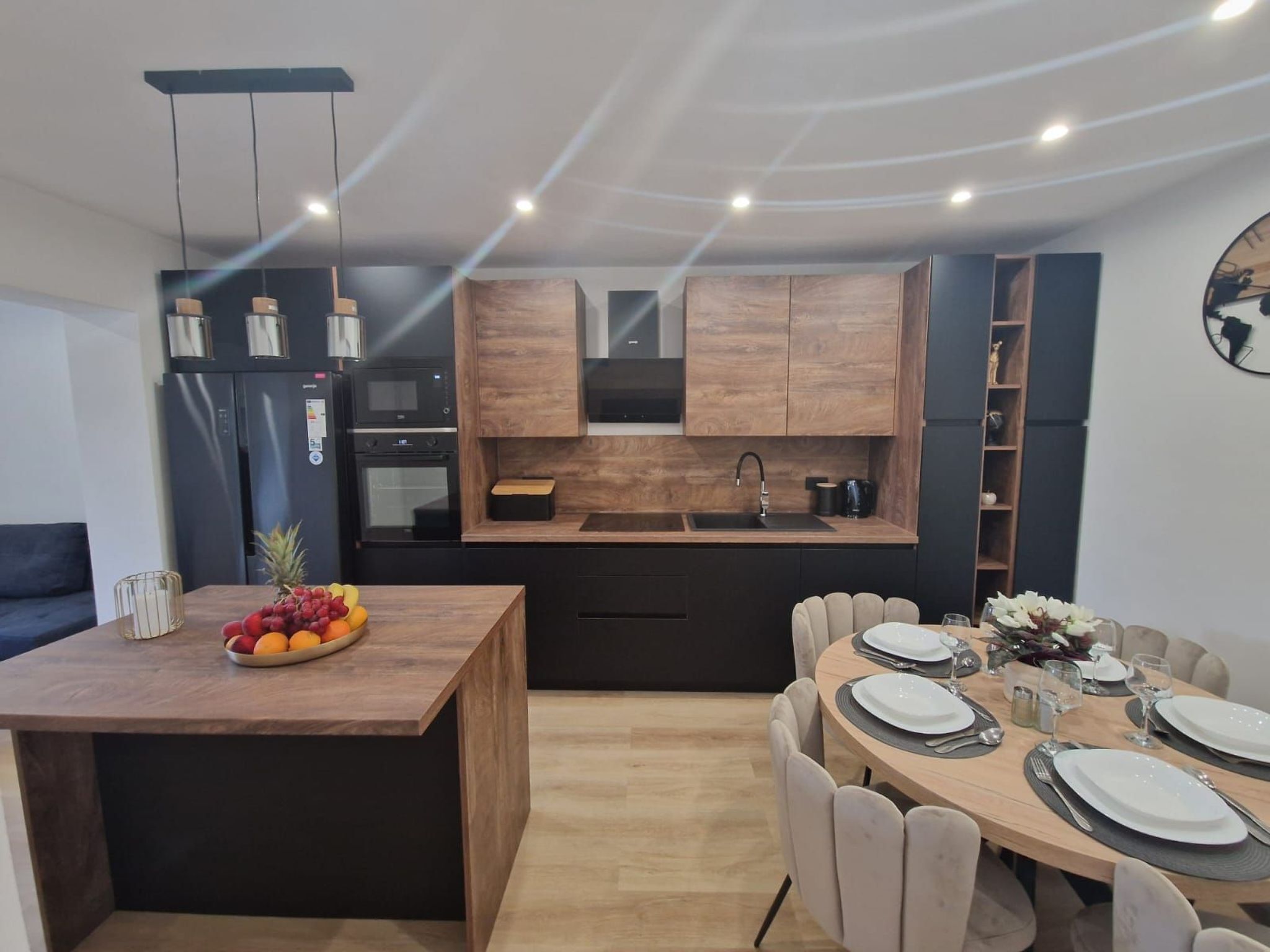 A modern kitchen with wooden cabinets, a built-in oven, and a dining area with a wooden table set for four.