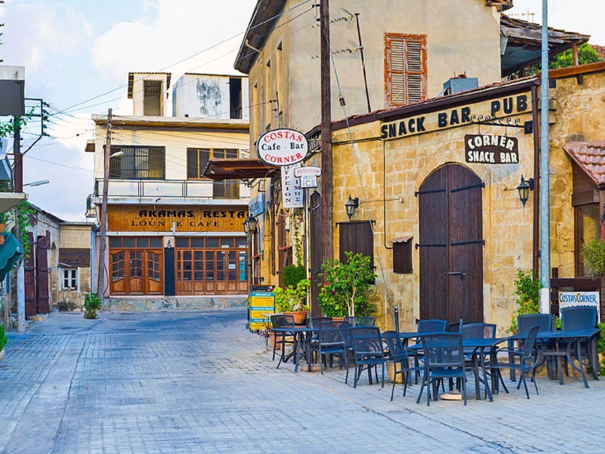 Una calle con mesas al aire libre en un bar de tapas, una cafetería y un restaurante.