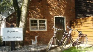 A brick building with a sign reading "Logement" and "1 Ganzekucken". Two bicycles are parked in front. - Unterbringung Ganzekuken by Interhome (Vriescheloo)
