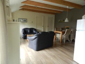 A living room with a sofa, a dining table with chairs, and a kitchen area. - Unterbringung Ganzekuken by Interhome (Vriescheloo)