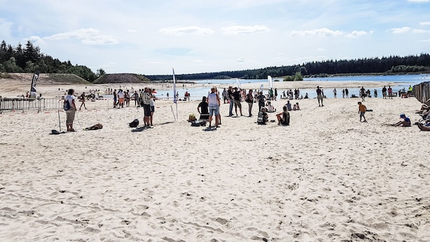 En sandstrand med folk och en klar himmel.