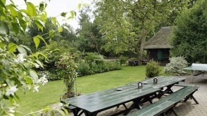 Ett picknickbord placerat på en innergård med ett tegelgolv, med en gräsyta och träd i bakgrunden.