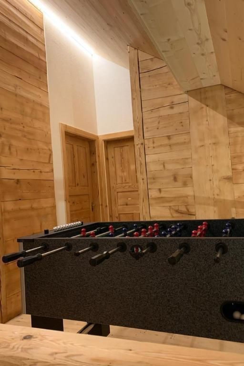 Ein Kicker-Tisch in einem Raum mit Holzwänden und einer geneigten Decke.