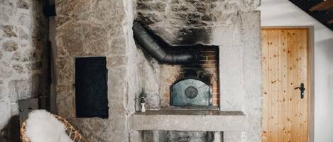 Una chimenea de piedra con chimenea, una silla blanca y una puerta de madera.