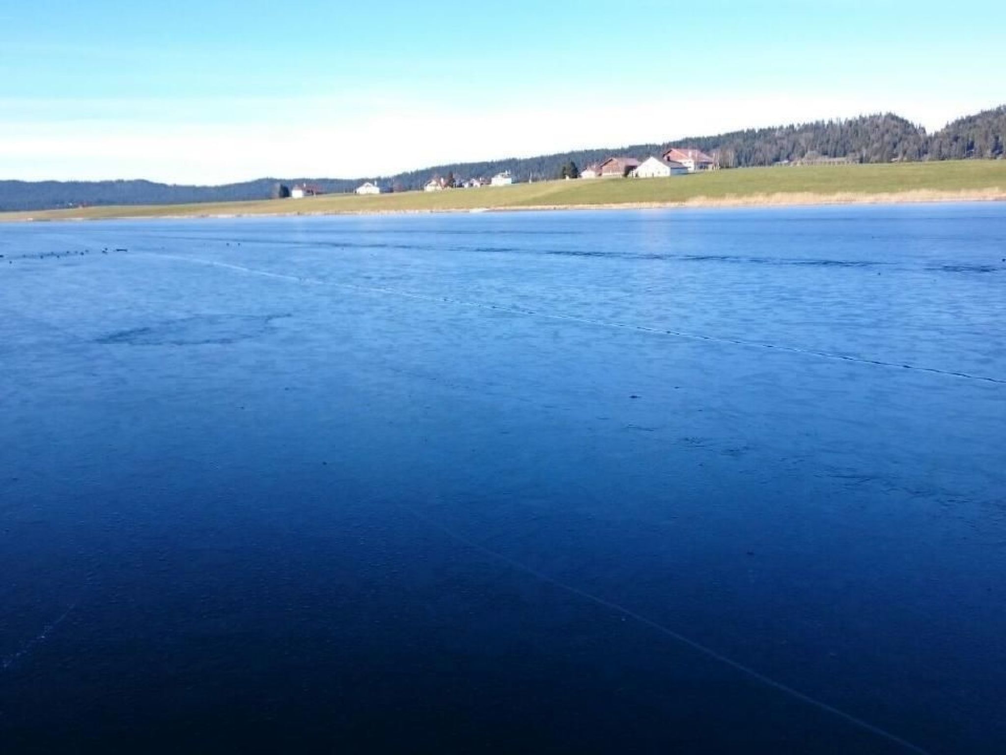 Um lago congelado com casas ao fundo.