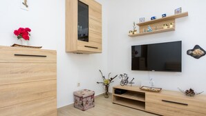 Una sala de estar moderna con muebles de madera, un televisor de pantalla plana y objetos decorativos en estantes.
