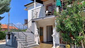 A two-story building with a stone staircase leading to a wooden door. - Wohnung Volaric by Interhome (Polje)