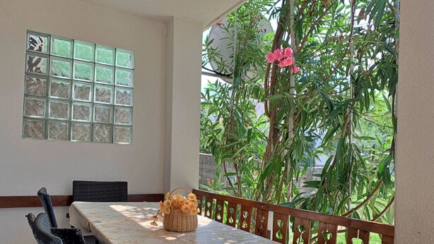 A dining area with a long table, chairs, and a view of greenery through a window. - Wohnung Volaric by Interhome (Polje)